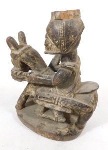 A late 19thC West African wooden carving, of a man in a headdress, mounted on a horse or donkey, and holding a staff, raised on an oval base, traces of white pigment, 21cm wide. - 2