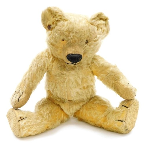 An early 20thC vintage Teddy bear, with a humped back, centre stitched body, jointed arms, legs and head, the snout stitched, eyes lacking, right ear bears a button, 40cm high.