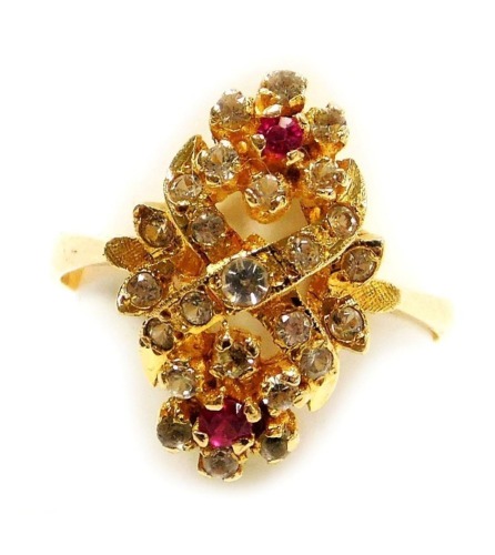 A ruby and white sapphire ring, in a double flower head and cross design, in a yellow metal high claw basket oval mount, stamped 585, size M, 3.1g.