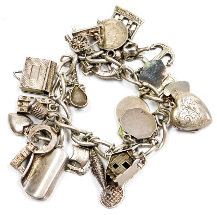 A silver charm bracelet, on a heart shaped padlock clasp, with safety chain, and twenty six charms, silver, enamel and white metal, as fitted, 66.3g all in.