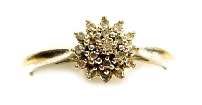 A platinum and diamond flower head ring, of three tier form, in a basket mount, set with nineteen tiny diamonds, size O 1/2, 1.8g.