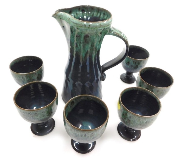 A late 20thC Woburn pottery water set, with mottled green above blue glaze, impressed marks, comprising water jug and six stemmed cups. (7)