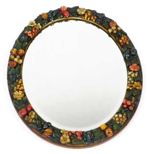 An early 20thC barbola type oval wall mirror, inset bevelled glass, the frame moulded with fruit and flowers, 54cm x 44cm.