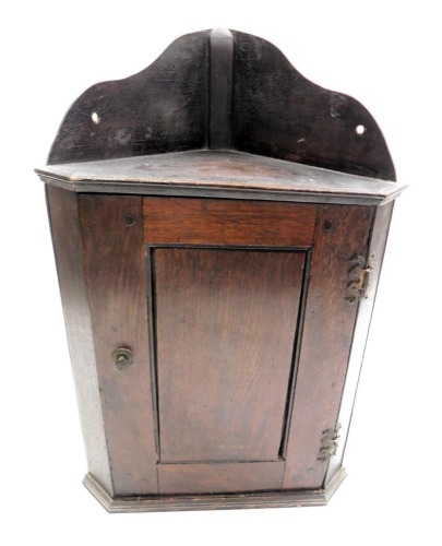 A 19thC oak wall hanging corner cupboard, the panelled door opening to reveal a single shelf, raised on a plinth base, 51cm high, 33.5cm wide.
