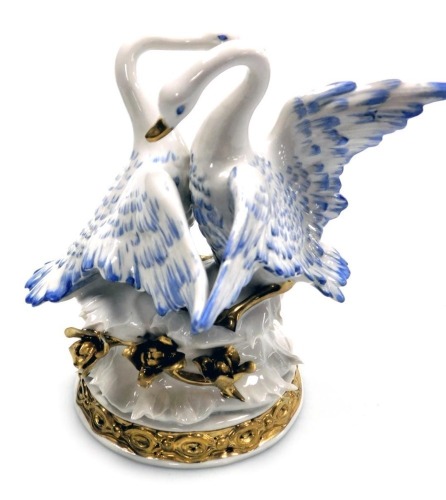 A continental porcelain figure group of a pair of courting swans, raised on a naturalistic base with flowers, gilt heightened, painted marks, 16cm high.