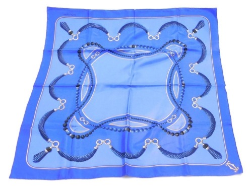A Must de Carlier silk scarf, decorated with gold and lapis lazuli jewellery against a blue ground, 82cm x 82cm.