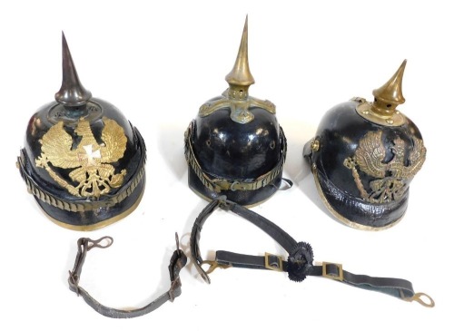 Three German Pickelhaubes, two bearing badges of the Prussian Eagle, in various condition.