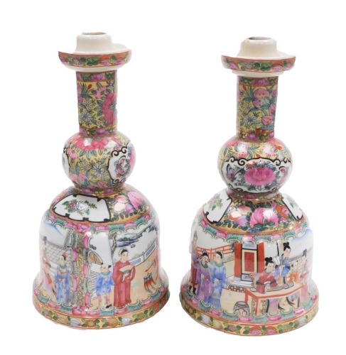 A pair of late Chinese Canton porcelain candlesticks, each with a circular drip pan and a bell shaped base, decorated with figures, fruit, flowers, etc., unmarked, 30cm high.