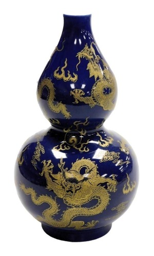 A 20thC Chinese porcelain vase, of double gourd form, decorated with five claw dragons on a blue ground, blue six character Kangxi mark to underside, 26.5cm high.