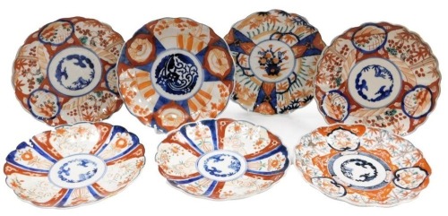 Seven Meiji period Japanese porcelain Imari plates, each of scalloped form, each variously decorated, some with transfer printed designs, each 22cm diameter.