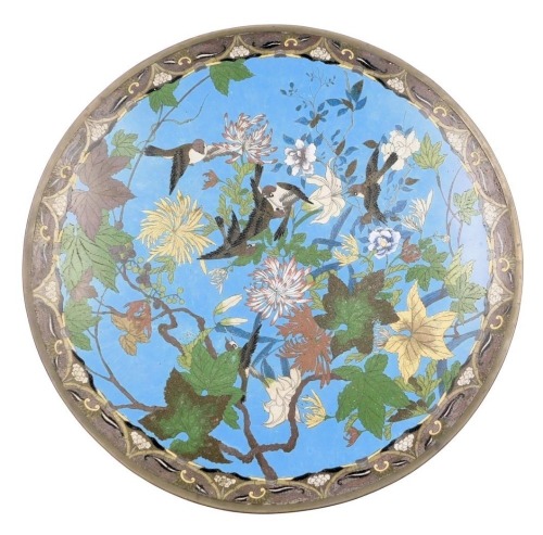 A Meiji period Japanese cloisonne charger, decorated with birds amongst chrysanthemum and other flowering branches, on a blue ground within a floral repeat border, 55.5cm diameter.