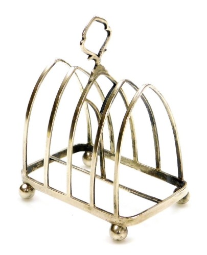 A George V silver four division toast rack, of Gothic form, raised on four ball feet, London 1912, 3.25oz.