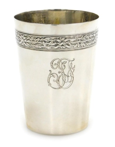 A late 19thC Continental beaker, white metal, decorated with a band of laurel leaves, tied at intervals, above an engraved monogram, bears marks, 3.13oz.