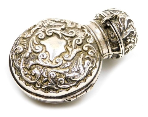 A Victorian silver scent bottle holder, embossed with birds and foliate scrolls, vacant shield reserves, opening to reveal a glass bottle for J&E Atkinson, 24 Bond Street London, Chester 1897, 1.26oz.