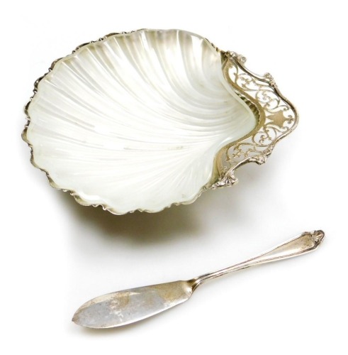 A George V silver and frosted glass scallop shell butter dish, with a foliate pierced handle, raised on three ball feet, together with a butter knife, Mappin and Webb, Birmingham 1915, 2.86oz.