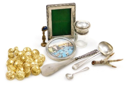 A group of small silver, comprising a silver handled shoe horn, cut glass toilet jar with silver screw lid, and two strut photograph frames, together with plated wares, military buttons, brass seal, and a Scottish silver mounted bird's claw brooch. (a qua