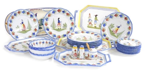 A group of Henriot Quimper pottery table wares, traditionally painted with figures, within leaf borders, comprising four twin handled serving trays, a fish serving platter, eight dinner plates, three dessert bowls, eight side plates, and a three piece cru