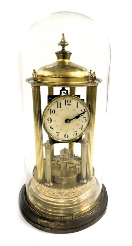 An early 20thC brass anniversary clock, the circular dial bearing Arabic numerals, single barrel movement, the case with a circular top raised on six fluted columns, above an embossed circular base, with glass dome, key and pendulum, 44cm high.