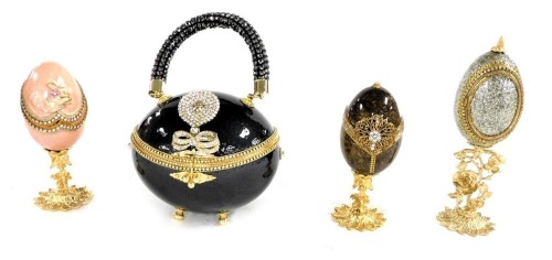 A novelty ostrich egg handbag, with paste set decoration, boxed, together with three novelty and decorative eggs, boxed. (4)