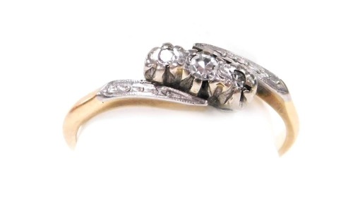 A 9ct gold platinum and diamond three stone ring, in a cross over setting, size O, 1.9g.