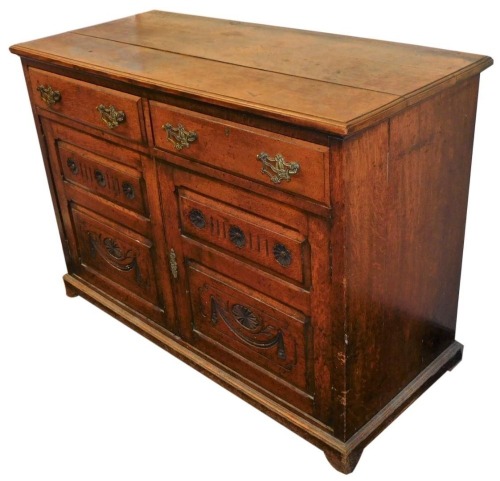A Victorian oak dresser base, with two drawers over a pair of carved panel doors, raised on bracket feet, 87cm high, 122cm wide, 53.5cm deep.
