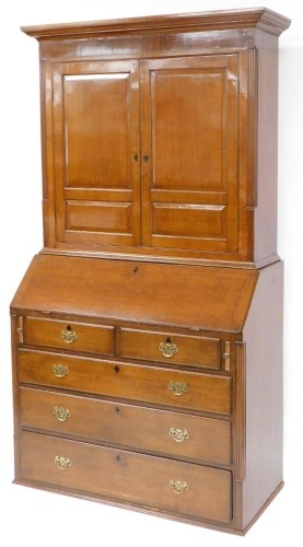 A George III oak bureau bookcase, the outswept pediment over a pair of panelled doors enclosing two adjustable shelves, above a fall flap, resting on skivers, enclosing an arrangement of doors, drawers and recesses, above two short over three long graduat