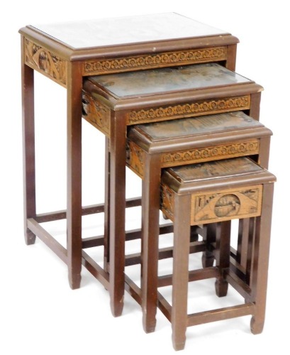 A mid 20thC quartetto of Hong Kong carved wooden occasional tables, each top carved with figures in a garden setting, raised on square legs, largest table 67cm high, 51cm wide, 35cm deep.