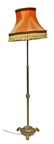 An early 20thC brass standard lamp, with a frill salmon pink coloured shade, 191cm high.