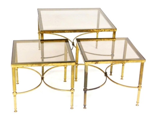 A vintage late 20thC brass nest of occasional tables, each of square form inset with a glass top, largest table, 47cm high, 67cm wide.