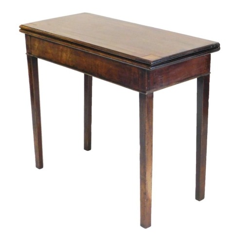 A George III mahogany fold over tea table, raised on tapering square legs, 74cm high, 86cm wide, 39cm deep.