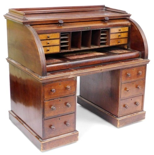 A Victorian mahogany cylinder bureau, opening to reveal recesses and six short burr walnut drawers, above a pull out writing surface, inset with tooled leather, over twin pedestals, each with three drawers, raised on plinth bases, 116cm high, 122cm wide, 