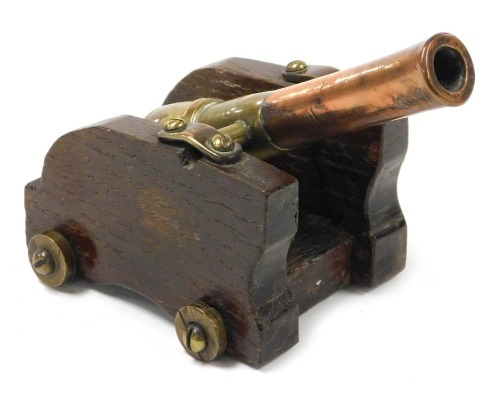 A miniature scratch built brass and copper cannon, with spring loaded action, mounted on oak carriage with brass wheels, 15.5cm long.