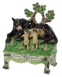 An early 19thC Staffordshire figure group, modelled as Remus and Romulus suckling a she wolf, on a titled table base, 21.5cm high. (AF)