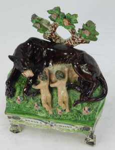 An early 19thC Staffordshire figure group, modelled as Remus and Romulus suckling a she wolf, on a titled table base, 21.5cm high. (AF) - 2
