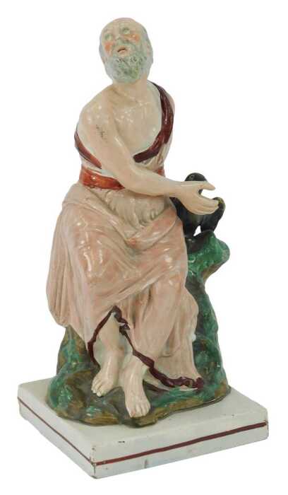 An early 19thC Staffordshire figure, modelled as Elijah and the Raven, 25cm high.