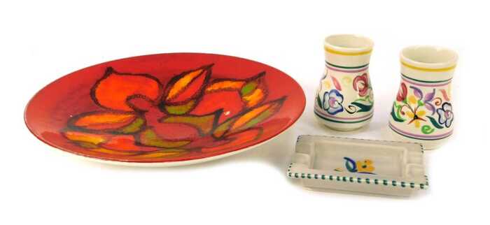 Four items of Poole pottery, comprising a Poole Delphis charger on an orange ground, 27cm wide, two circa 1960s Poole bud vases, 8cm high, and an ashtray with floral centre, 11cm wide. (4)