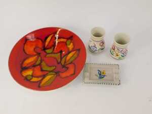 Four items of Poole pottery, comprising a Poole Delphis charger on an orange ground, 27cm wide, two circa 1960s Poole bud vases, 8cm high, and an ashtray with floral centre, 11cm wide. (4) - 2