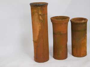 Three terracotta chimney pots, comprising one with fluted top, 75cm high, another straight example, 70cm high, and a straight and ribbed example, 104cm high. (3, AF) - 3