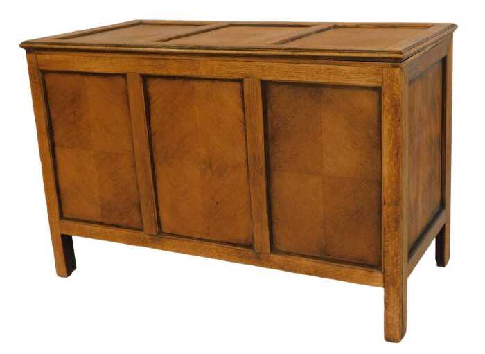A 20thC oak blanket box, with three sectional veneered top, panelled front and sides, turned on stiles, 61cm high, 92cm wide, 47cm deep.