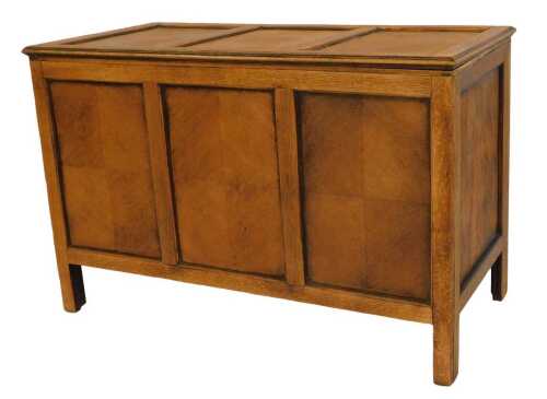 A 20thC oak blanket box, with three sectional veneered top, panelled front and sides, turned on stiles, 61cm high, 92cm wide, 47cm deep.