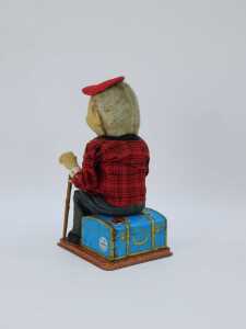 A 20thC tinplate figure of a gentleman seated with walking cane on Russian suitcase, by Roscoe, 30cm high. (AF) - 3