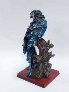 A 20thC resin sculpture of a parrot on a perch, with pink breast and blue feathers, on a rectangular hardwood base, 58cm high, 26cm x 24cm. - 2