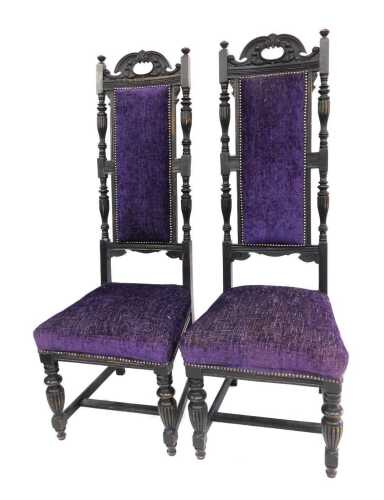 A pair of Victorian ebonised hall chairs, each with a high carved raised back, with later purple upholstered seats and backs, 140cm high, 55cm wide.