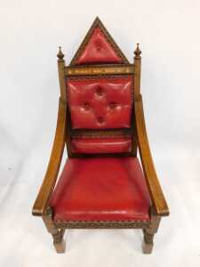 An Elizabeth II Silver Jubilee oak throne chair, with red leather upholstery, and carved and raised back, with crested and button decoration bearing gilded inscription, 150cm high, 69cm wide, 70cm deep. - 2