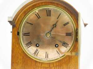 An early 20thC oak cased mantel clock, the silvered circular dial bearing Arabic numerals, eight day, the case of arched form, the moulded base on compressed brass feet, 29cm high. - 2