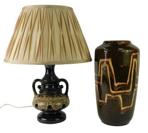 A West German pottery vase, of cylindrical form decorated with abstract line decoration against a mottled glaze ground, 38cm high, together with a brown glazed pottery two handled table lamp, 38cm high, with shade.