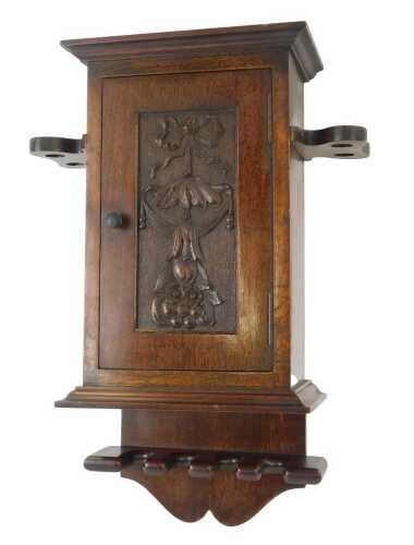 An early 20thC and later oak wall hanging pipe box, the top with an outswept pediment above a bow, fruit and floral carved door enclosing a single shelf, the body flanked by two shaped recesses for pipes, the base with four sections to hold pipes, 42cm hi