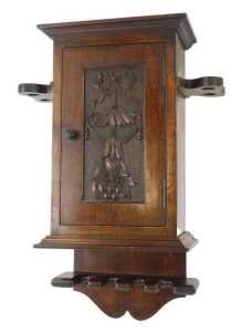 An early 20thC and later oak wall hanging pipe box, the top with an outswept pediment above a bow, fruit and floral carved door enclosing a single shelf, the body flanked by two shaped recesses for pipes, the base with four sections to hold pipes, 42cm hi