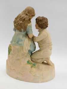 A 20thC bisque figure group, depicting a young girl seated holding fabric beside a kneeling boy, 37cm high. - 2