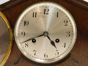 An early 20thC oak cased mantel clock, the silvered circular Arabic numeral dial with eight day movement, the case with a shaped top and applied decoration, on four compressed bun feet, 25cm high. - 2